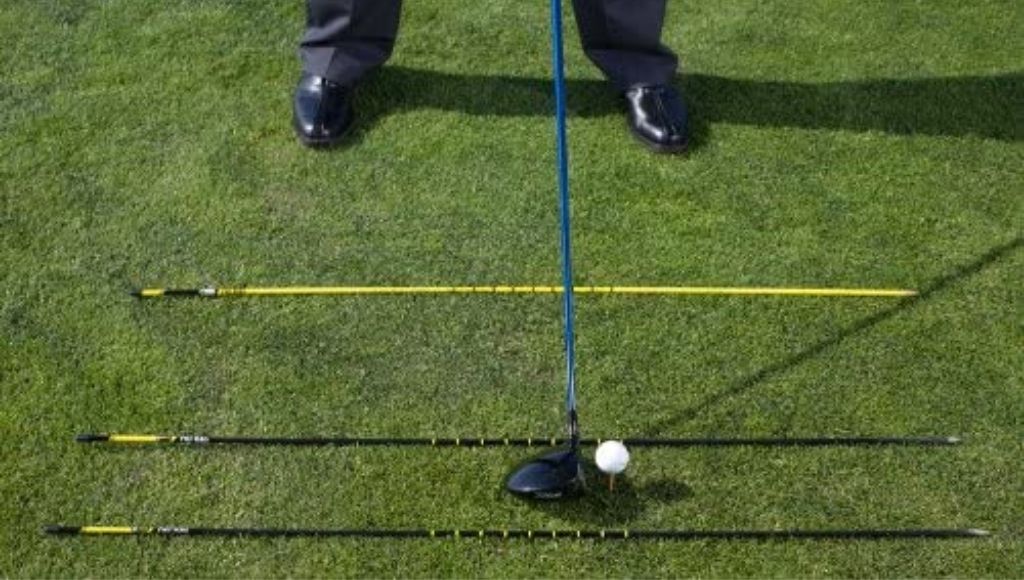 A man align his 3 golf alignment sticks for a perfect shot