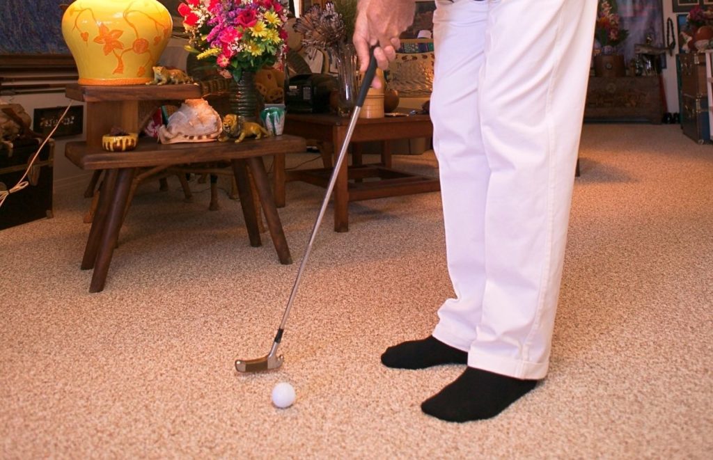 A man putting on his carpet, a great option when considering how to practice golf at home