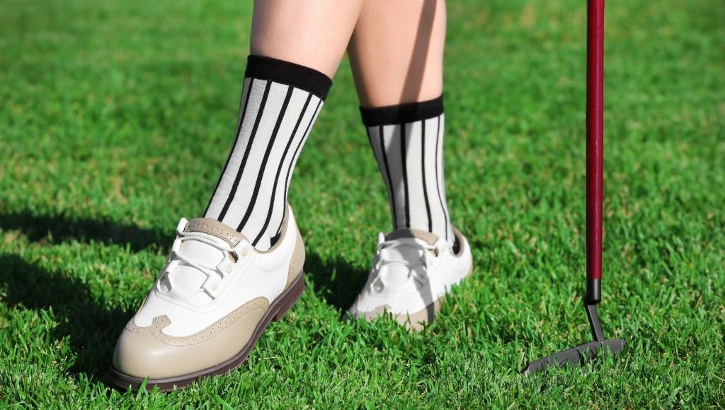 A girl is standing on the golf course wearing golf socks