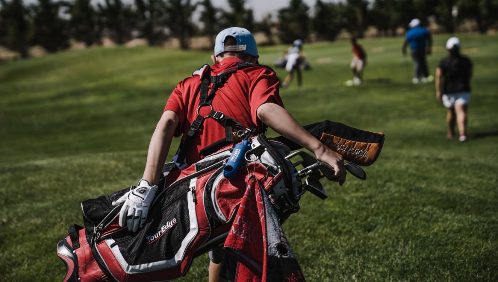 A man carrying a golf bag in his back