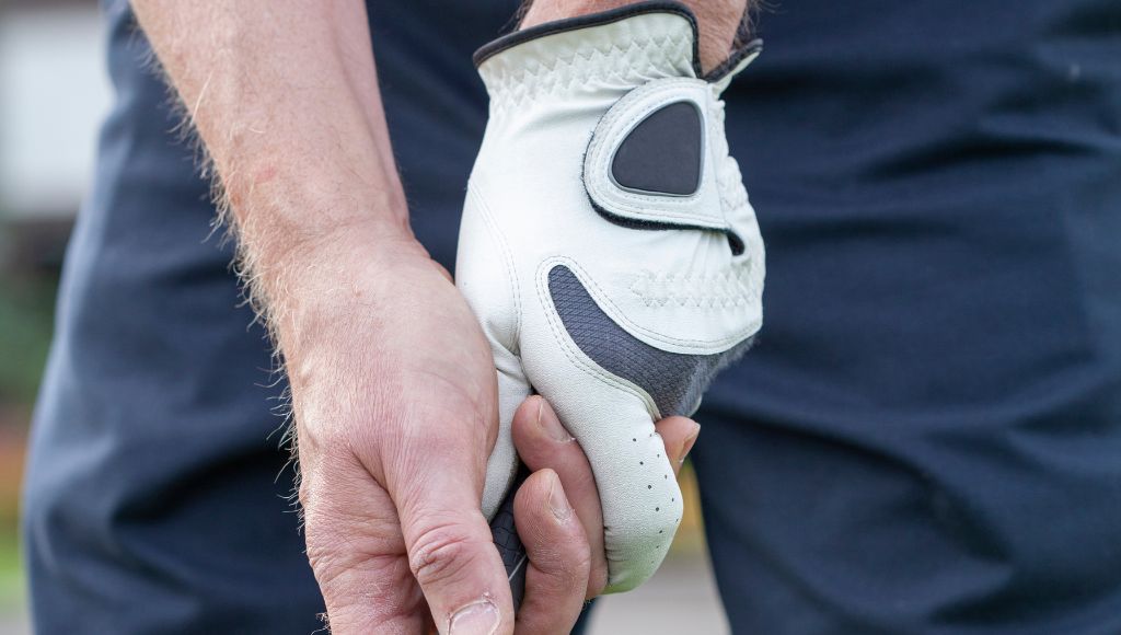A man golfer in a leather golf glove gripping a golf club