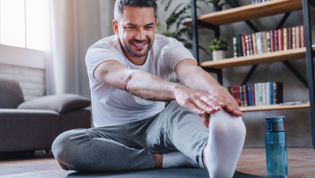 Handsome man doing hamstring stretch exercise at home