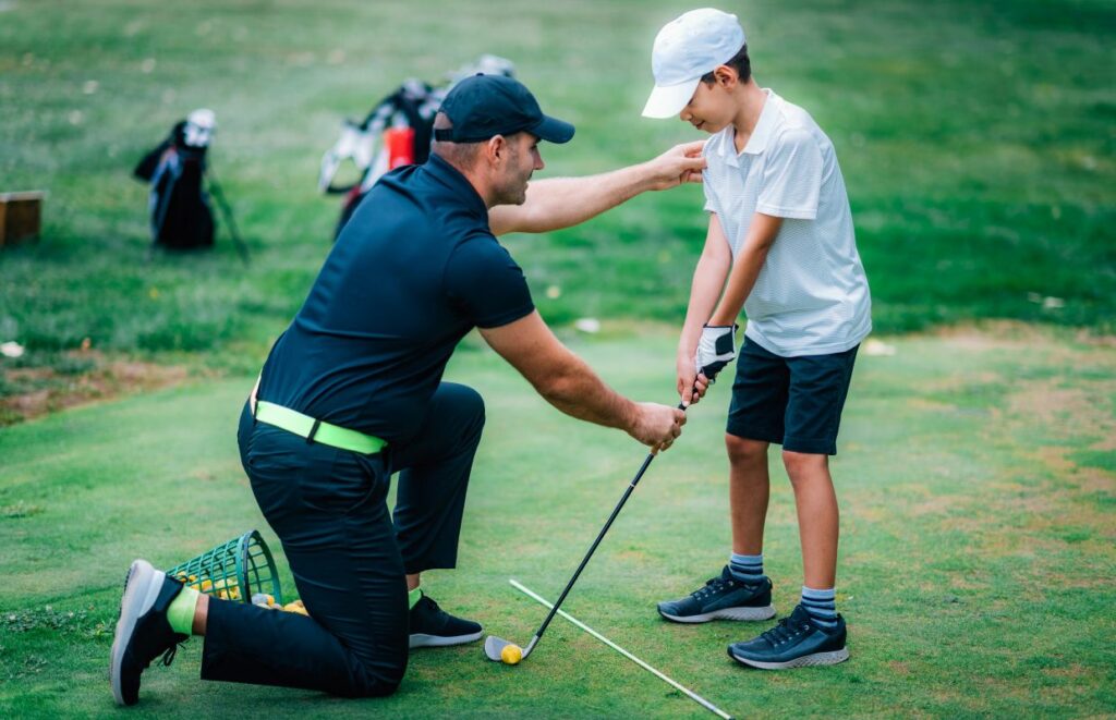 A parent coaching his son golf fundamentals